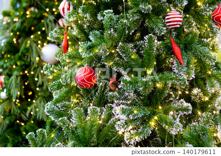 beautiful christmas tree covered in bright golden fairy lights and red swirl ball ornaments. festive background beautiful christmas tree covered in bright golden fairy lights and red swirl ball ornaments. festive background 140179611
