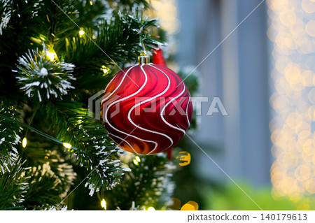 red ornament ball hanging on christmas tree. blurry golden light curtain backdrop on the right side 140179613