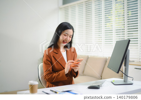 Asian businesswoman working at desk in modern office using smartphone and computer, professional corporate lifestyle Asian businesswoman working at desk in modern office using smartphone and computer, professional corporate lifestyle 140179806