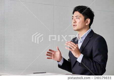 一位三十多歲的日本商人用手勢和肢體語言進行解釋。 一位三十多歲的日本商人用手勢和肢體語言進行解釋。 140179833