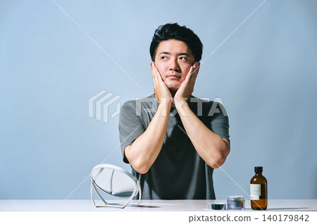 A Japanese man in his 30s cupping his cheeks with both hands after skincare, conveying an image of beautiful, moisturized skin. A Japanese man in his 30s cupping his cheeks with both hands after skincare, conveying an image of beautiful, moisturized skin. 140179842