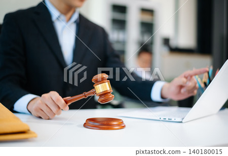Asian lawyer in suit holding gavel and using laptop with justice scales on desk. Ideal for law, judgment, legal advice, courtroom Asian lawyer in suit holding gavel and using laptop with justice scales on desk. Ideal for law, judgment, legal advice, courtroom 140180015