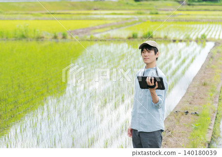 A young man uses a tablet to farm. A young man uses a tablet to farm. 140180039
