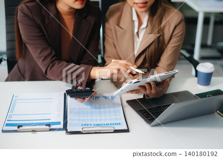 Two young business women sitting at table.colleagues working together, have a discussion and using tablet Two young business women sitting at table.colleagues working together, have a discussion and using tablet 140180192
