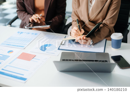 The business team analyzes revenue charts and graphs with laptop and tablet.Business analysis The business team analyzes revenue charts and graphs with laptop and tablet.Business analysis 140180210