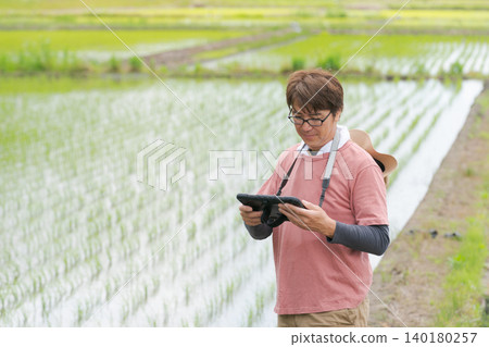 A man manages his farm using a tablet. A man manages his farm using a tablet. 140180257