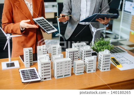 Professionals for a greener future. Showcasing renewable energy solutions with solar panels, wind turbines, and a model house. Professionals for a greener future. Showcasing renewable energy solutions with solar panels, wind turbines, and a model house. 140180265