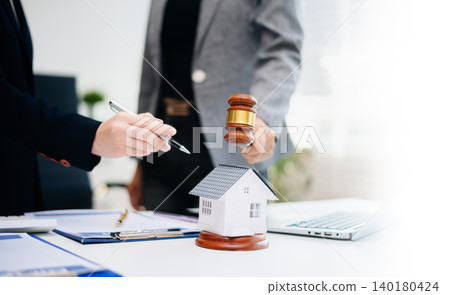 Judge gavel striking next to house model, symbolizing real estate law, legal decision, property auction, contract agreement, and home ownership. Judge gavel striking next to house model, symbolizing real estate law, legal decision, property auction, contract agreement, and home ownership. 140180424