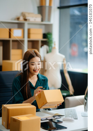 Asian woman prepares parcels and checks online orders on tablet and laptop for delivery online shopping Asian woman prepares parcels and checks online orders on tablet and laptop for delivery online shopping 140181070