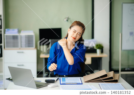 Overworked young Asian businesswoman office worker suffering from neck pain after had a long day Overworked young Asian businesswoman office worker suffering from neck pain after had a long day 140181352
