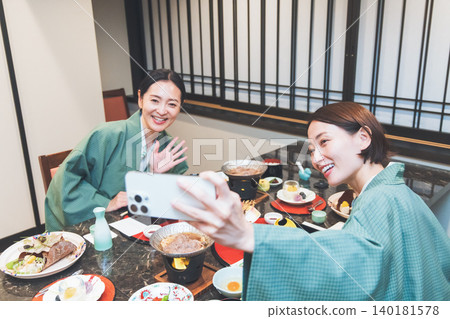 一位身穿浴衣的女子在日式旅館用餐時面帶微笑,拍下了一張紀念照。 一位身穿浴衣的女子在日式旅館用餐時面帶微笑,拍下了一張紀念照。 140181578