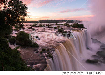 Majestic peaceful sunset lighting flowing water of beautiful iguazu falls Majestic peaceful sunset lighting flowing water of beautiful iguazu falls 140181858