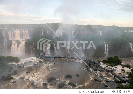 Majestic iguazu falls pouring powerful water and mist across scenic landscape Majestic iguazu falls pouring powerful water and mist across scenic landscape 140181859