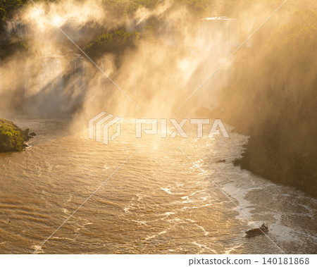 Fierce and powerful mist over iguazu falls glowing in warm sunlight Fierce and powerful mist over iguazu falls glowing in warm sunlight 140181868