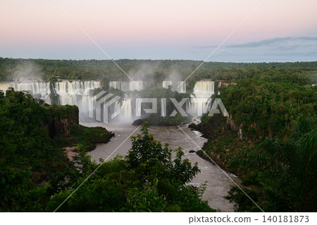 Majestic iguazu falls pouring into tranquil river surrounded by dense forest mist Majestic iguazu falls pouring into tranquil river surrounded by dense forest mist 140181873