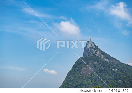 Majestic green mountain with tall statue reaching clear blue sky creates peaceful landscape of rio de janeiro 140181892