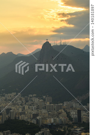 Serene sunset silhouette view of Christ Redeemer statue on Corcovado mountain overlooking Rio de Janeiro Brazil cityscape 140181897