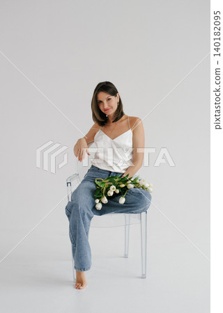 Woman Sitting on Transparent Chair with White Tulips Bouquet Woman Sitting on Transparent Chair with White Tulips Bouquet 140182095
