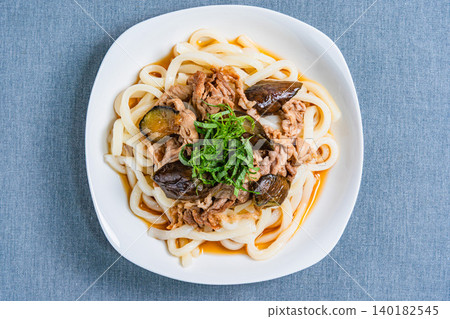 A photo of a chilled udon noodle dish with eggplant and pork, topped with shiso leaves, perfect for summer. 140182545