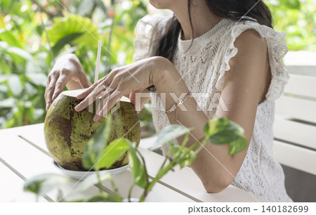 woman drinking fresh coconit in tropical outdoors garden cafe in bali indonesia woman drinking fresh coconit in tropical outdoors garden cafe in bali indonesia 140182699