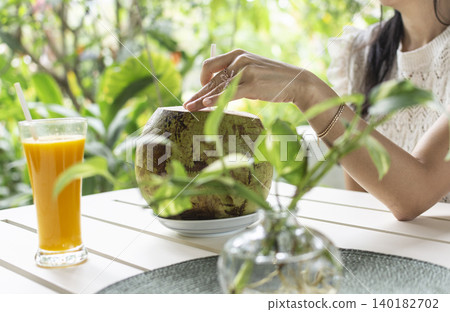 woman drinking fresh coconit in tropical outdoors garden cafe in bali indonesia woman drinking fresh coconit in tropical outdoors garden cafe in bali indonesia 140182702