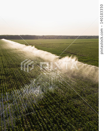 Agricultural watering pivot irrigation system on a corn field at sunset. Agricultural watering pivot irrigation system on a corn field at sunset. 140183350