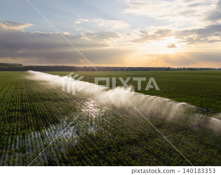 Agricultural watering pivot irrigation system on a corn field at sunset. Agricultural watering pivot irrigation system on a corn field at sunset. 140183353