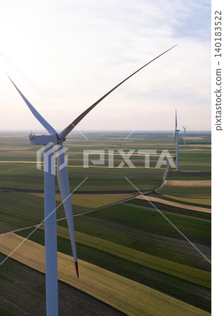 Aerial view of wind turbine on an agricultural filed at sunset. Close up of blades. 140183522