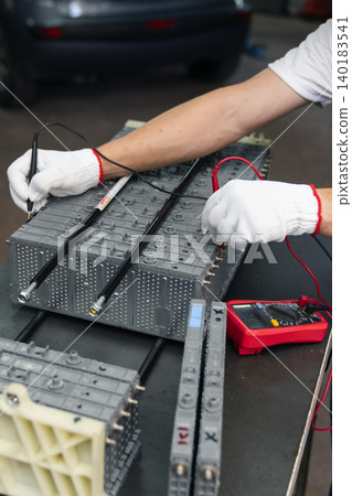 Serviceman repairs electric battery pack of hybrid car Serviceman repairs electric battery pack of hybrid car 140183541