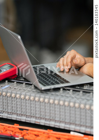 Serviceman repairs electric battery pack of hybrid car using laptop Serviceman repairs electric battery pack of hybrid car using laptop 140183545