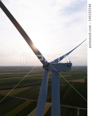 Aerial view of wind turbine on an agricultural filed at sunset. Close up of blades. Aerial view of wind turbine on an agricultural filed at sunset. Close up of blades. 140183546