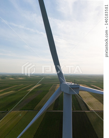 Aerial view of wind turbine on an agricultural filed at sunset. Close up of blades. Aerial view of wind turbine on an agricultural filed at sunset. Close up of blades. 140183581