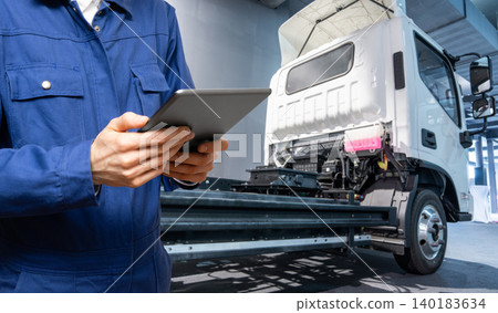Serviceman with digital tablet next to electric truck. Electric vehicles maintenance Serviceman with digital tablet next to electric truck. Electric vehicles maintenance 140183634
