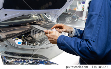 Serviceman with digital tablet on the background of the car in the car service. Serviceman with digital tablet on the background of the car in the car service. 140183645
