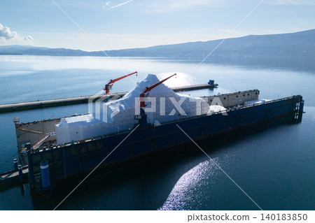 Aerial view of a luxury yacht refit, repair, service and maintenance in a floating dock at a marina. Aerial view of a luxury yacht refit, repair, service and maintenance in a floating dock at a marina. 140183850