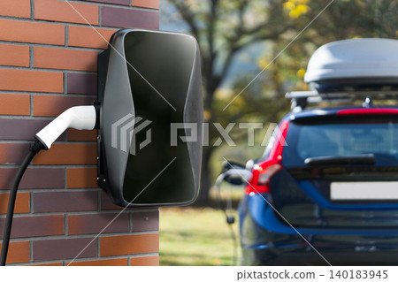 Charging electric car next to countryside house. Charging electric car next to countryside house. 140183945