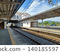 A rural train station with yellow tactile paving blocks, a colonial-style overpass beyond the tracks, and mountains and trees in the background. A rural train station with yellow tactile paving blocks, a colonial-style overpass beyond the tracks, and mountains and trees in the background. 140185597