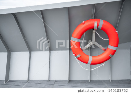 Orange lifebuoy or life preserver ring hanging on side wall of steel boat Orange lifebuoy or life preserver ring hanging on side wall of steel boat 140185762