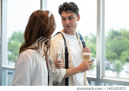 Asian woman girlfriend linking arms talking to white man boyfriend while walking in airport building Asian woman girlfriend linking arms talking to white man boyfriend while walking in airport building 140185825