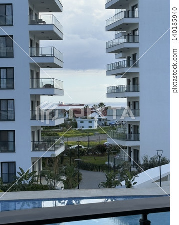 Modern beachfront resort architecture with balconies and pool under partly cloudy skies Modern beachfront resort architecture with balconies and pool under partly cloudy skies 140185940