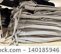 Stack of neatly folded gray pants with buttons and strings on wooden store shelf, suitable for background 140185946
