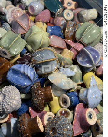Ceramic sculptures of colorful sea urchins displayed in an artistic heap, showcasing texture 140185948