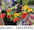 Bouquet of vibrant flowers featuring poppies, calla lilies, and lush green foliage outdoors 140185956