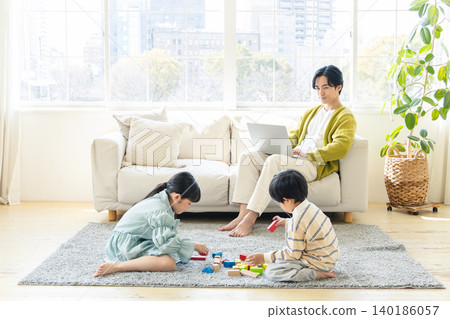 一位父親在客廳遠距辦公，孩子們則在室內玩耍。 140186057