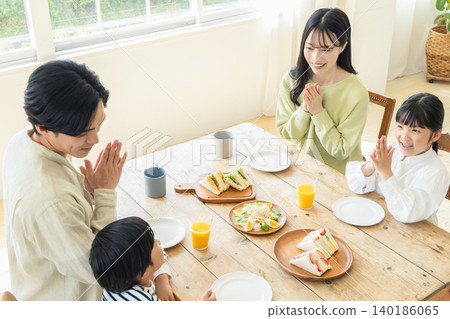 A family eating a meal in the dining room of their home. 140186065