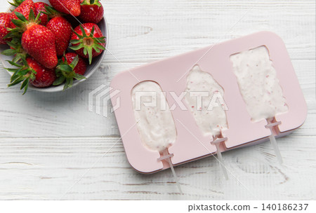 Preparing homemade strawberry yogurt popsicles on wooden background Preparing homemade strawberry yogurt popsicles on wooden background 140186237