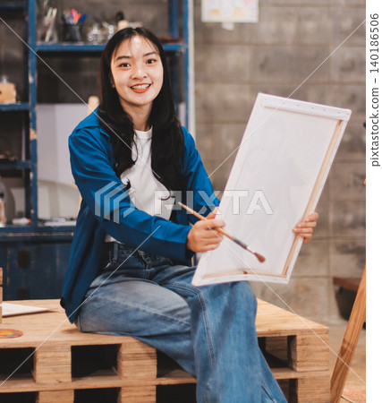 Female artist wears black hat posing near picture indoor the studio Female artist wears black hat posing near picture indoor the studio 140186506