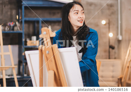 Female artist wears black hat posing near picture indoor the studio 140186516