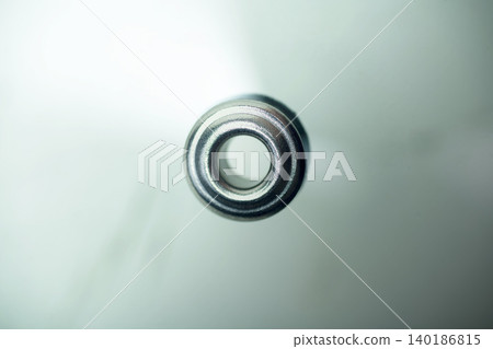 A detailed top-down macro photograph of a round metallic eyelet or steel washer, isolated on a soft blurred background, showcasing industrial minimalism and metallic texture A detailed top-down macro photograph of a round metallic eyelet or steel washer, isolated on a soft blurred background, showcasing industrial minimalism and metallic texture 140186815