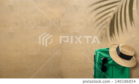 Top view of a green suitcase, straw hat, and sunglasses on sand with palm leaf shadow. Ideal for summer vacation and travel-related concepts with ample copy space Top view of a green suitcase, straw hat, and sunglasses on sand with palm leaf shadow. Ideal for summer vacation and travel-related concepts with ample copy space 140186854